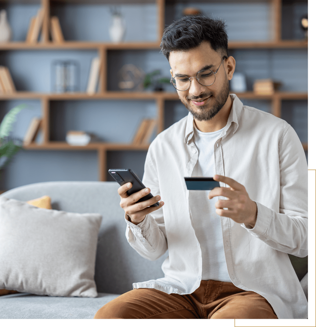 Man comparing credit card with smartphone while shopping online.