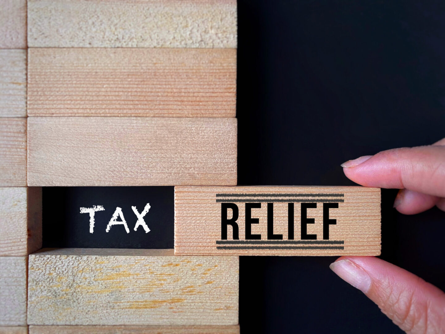 Wooden blocks with the words 'TAX RELIEF' being arranged.