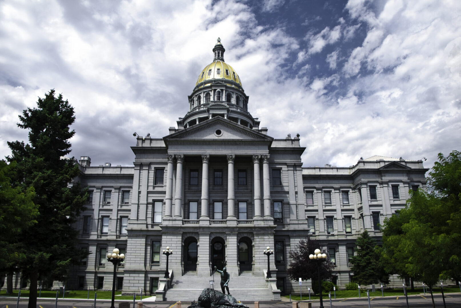 Historic government building with a golden dome under a partly cloudy sky.