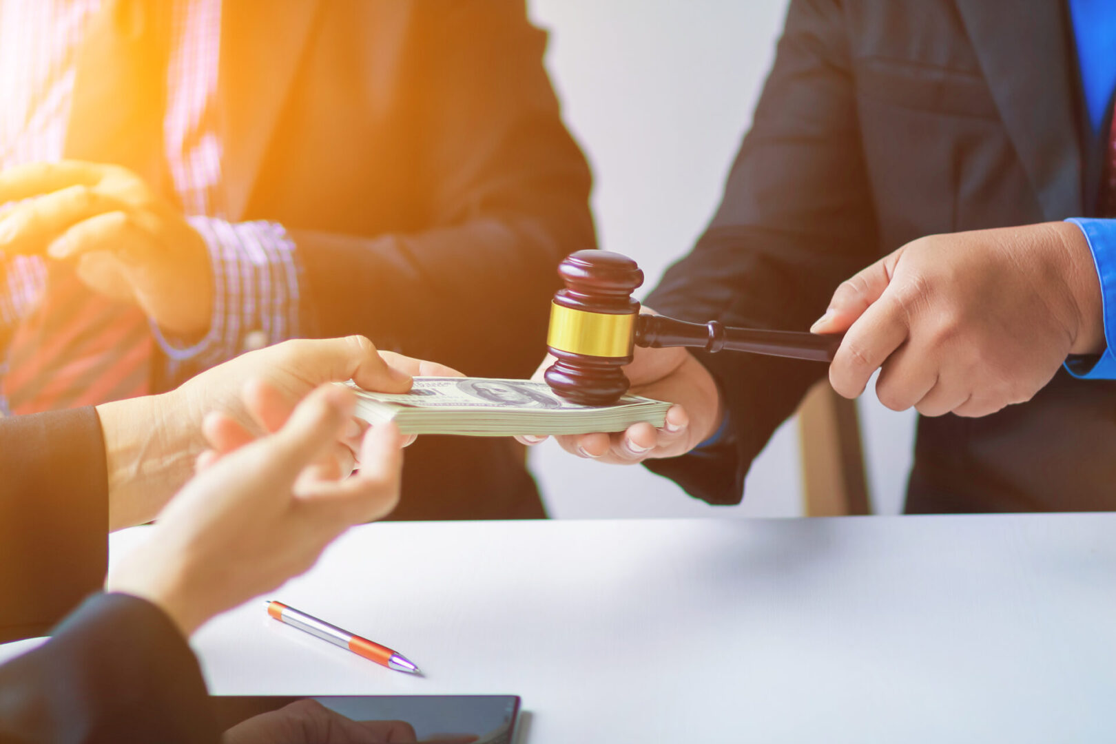 A person handing money to a judge holding a gavel.