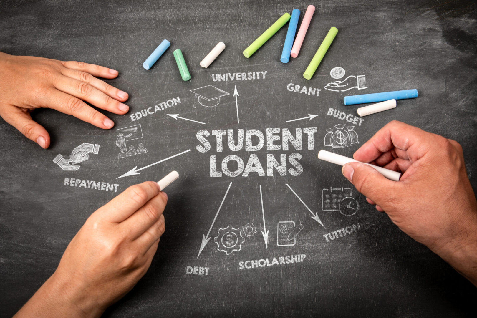 Hands drawing a student loans infographic with colorful chalk on blackboard.