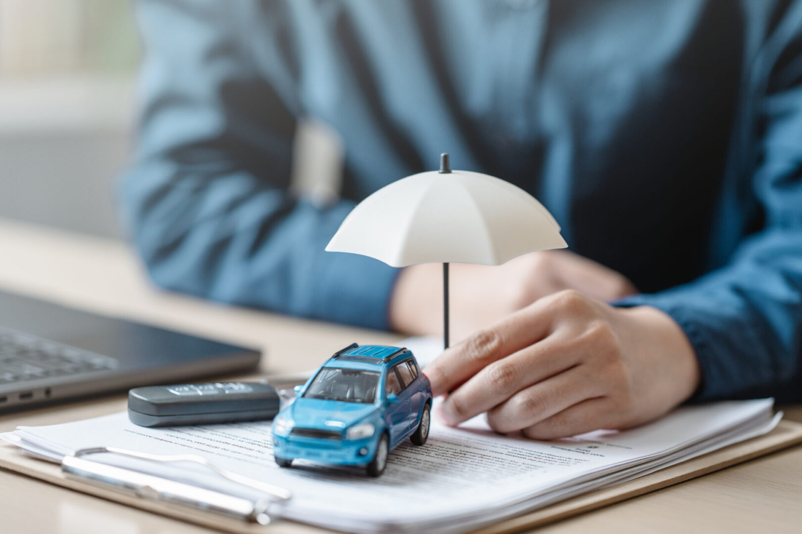 A small car model protected by a white umbrella held by a person.