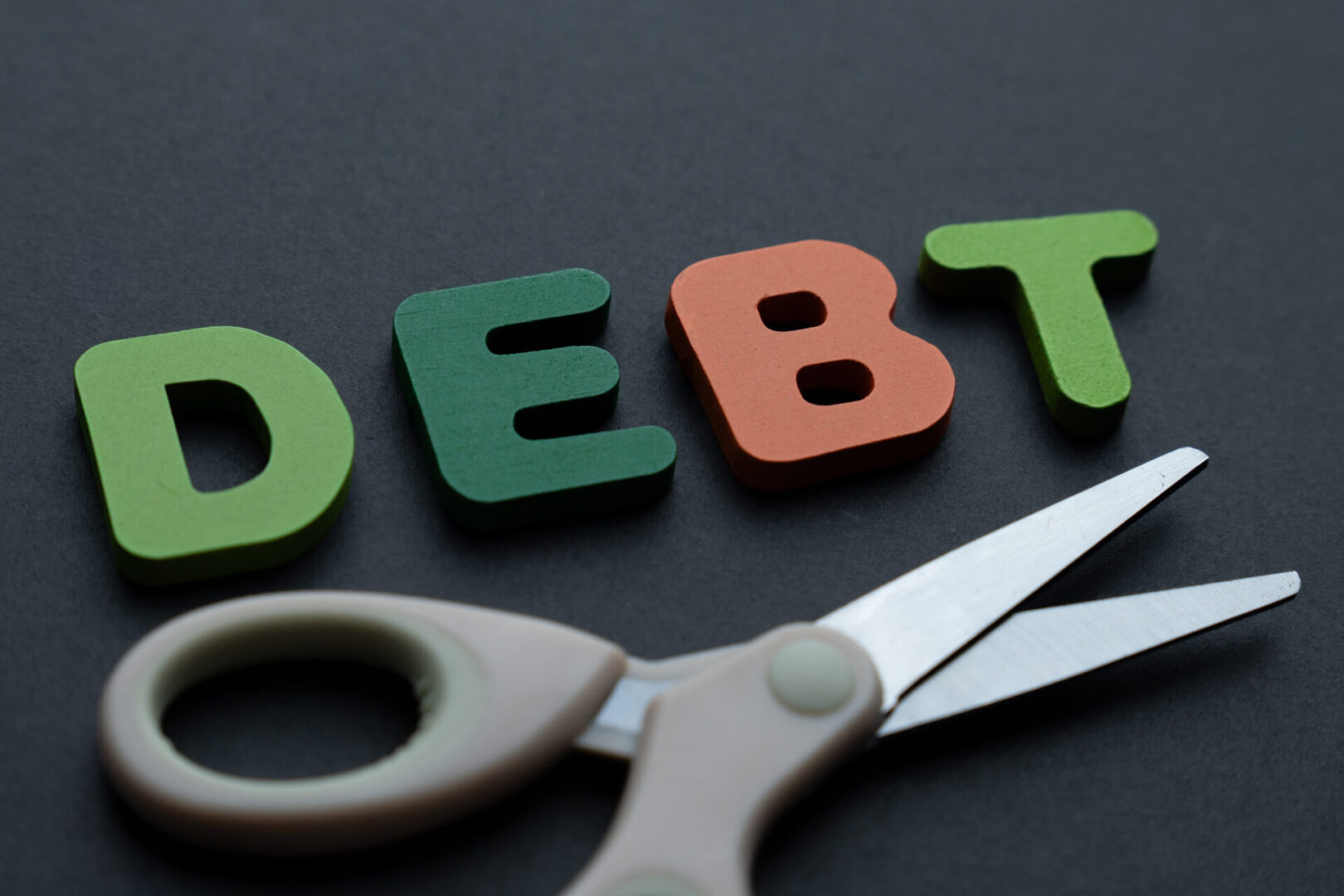 Scissors cutting through the word 'DEBT' symbolizing debt reduction.