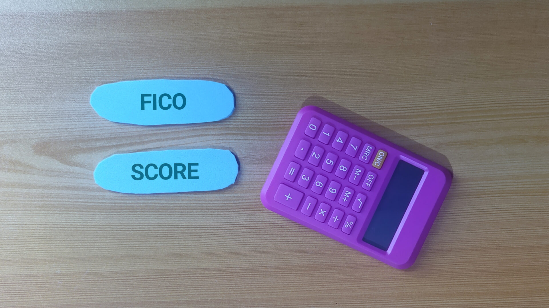 Calculator and FICO score cards on a wooden surface.